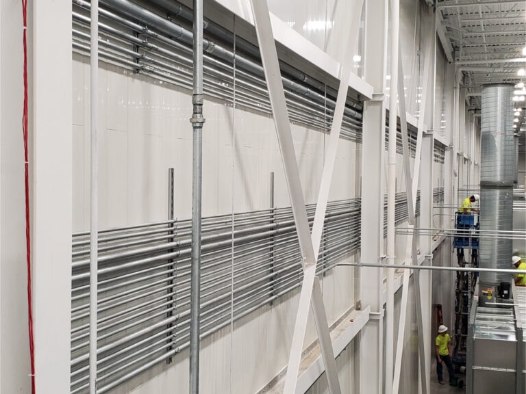 System construction — structural steel wall framing with workers