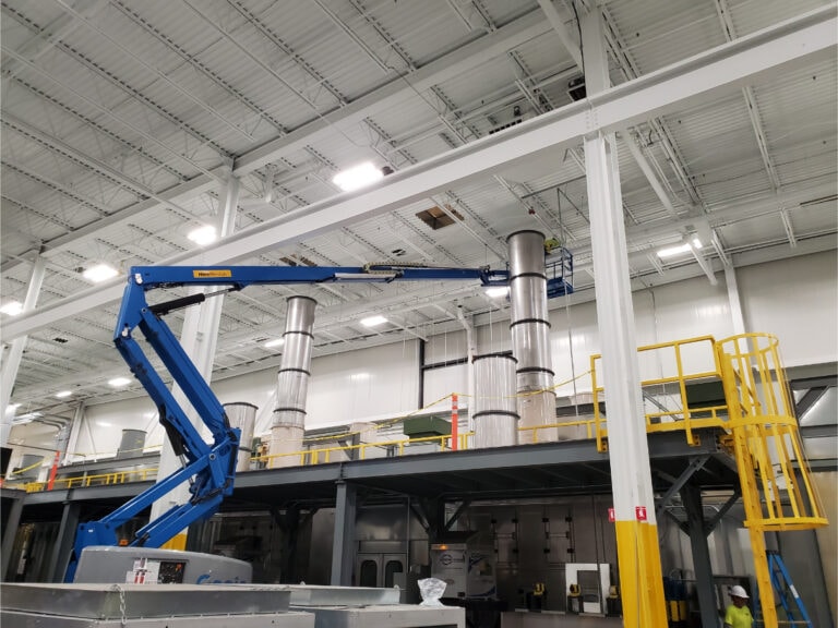 System construction — boom lift alongside mezzanine with exhaust stacks