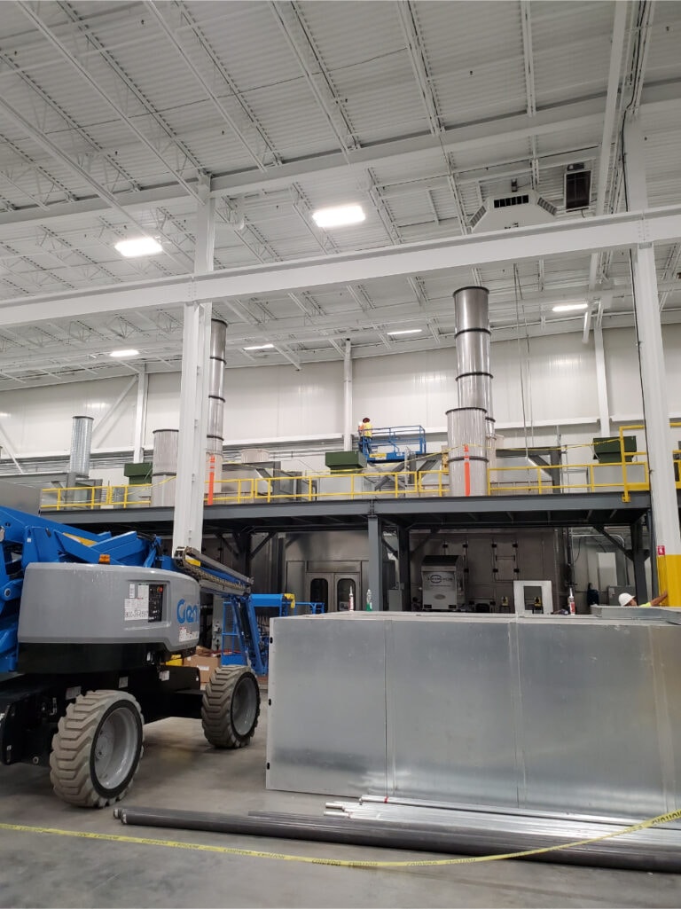 System construction — Genie boom lift beside mezzanine with ductwork