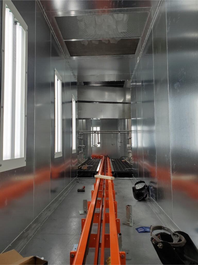 System construction — spray booth interior with orange conveyor track being installed